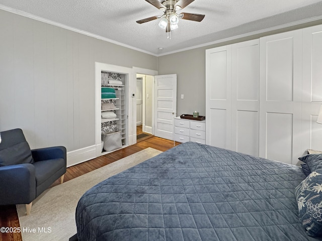 bedroom with ceiling fan, ornamental molding, wood finished floors, a closet, and a textured ceiling