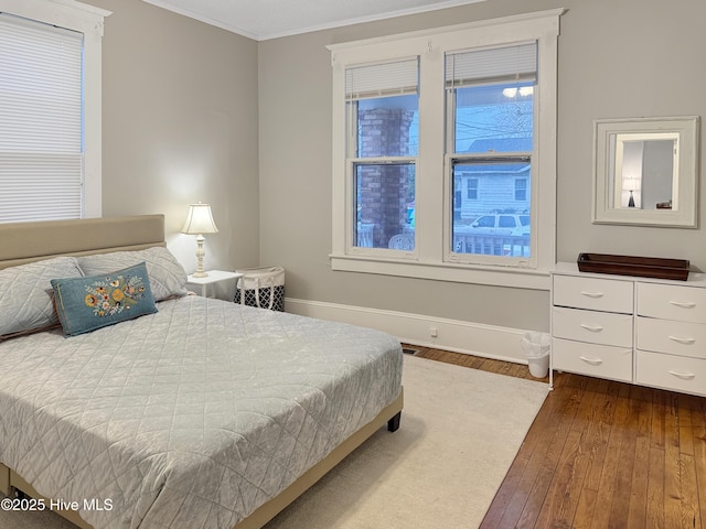 bedroom featuring dark wood-style floors, baseboards, and ornamental molding