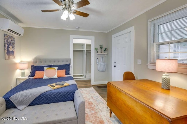 bedroom with ceiling fan, an AC wall unit, wood finished floors, and crown molding