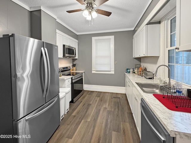 kitchen featuring appliances with stainless steel finishes, dark wood-style floors, a textured ceiling, white cabinetry, and a sink