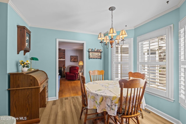 dining area with crown molding, light wood-type flooring, and a notable chandelier