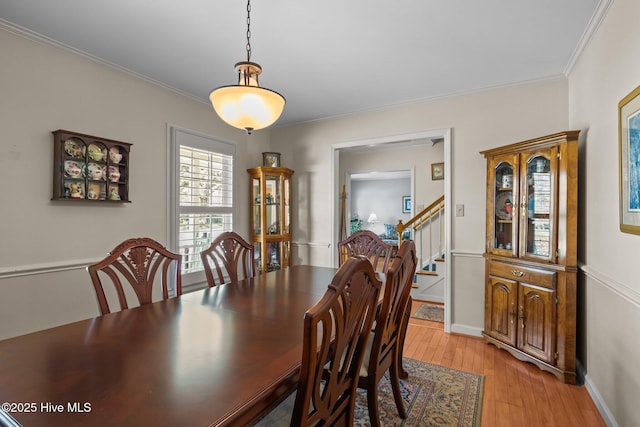 dining room with ornamental molding, stairway, light wood-style flooring, and baseboards