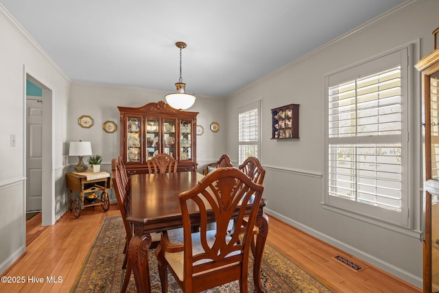 dining room with crown molding, baseboards, visible vents, and light wood-style floors