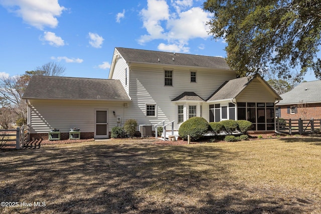 rear view of property with a sunroom, fence, central AC, and a yard