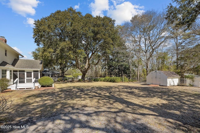 view of yard featuring a shed, an outdoor structure, a fenced backyard, and a sunroom