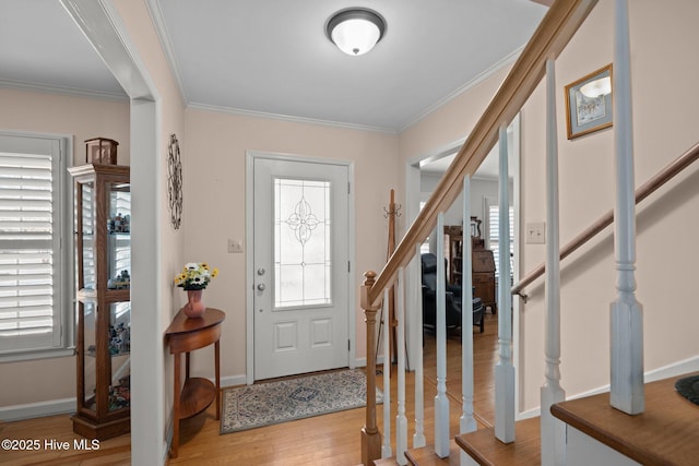 foyer featuring crown molding, stairs, baseboards, and wood finished floors