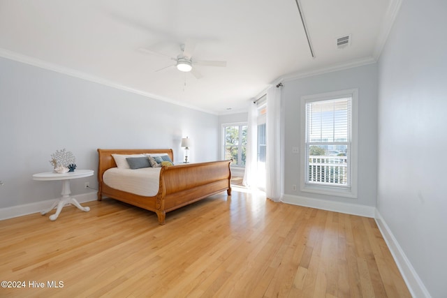 bedroom featuring ornamental molding, light wood finished floors, visible vents, and baseboards