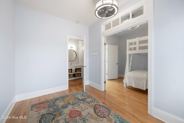 bedroom with ensuite bathroom, wood finished floors, and baseboards