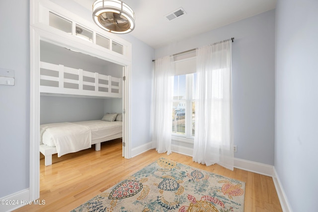 bedroom with visible vents, baseboards, and wood finished floors