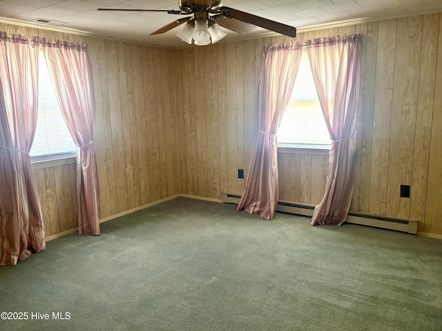 carpeted spare room with a ceiling fan, a healthy amount of sunlight, and wood walls