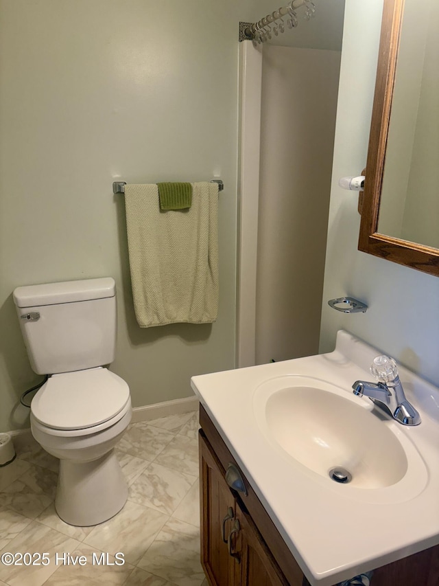 bathroom featuring toilet, marble finish floor, baseboards, and vanity