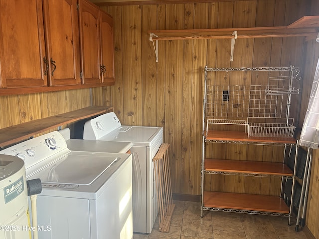 laundry room with washing machine and dryer, cabinet space, and wood walls