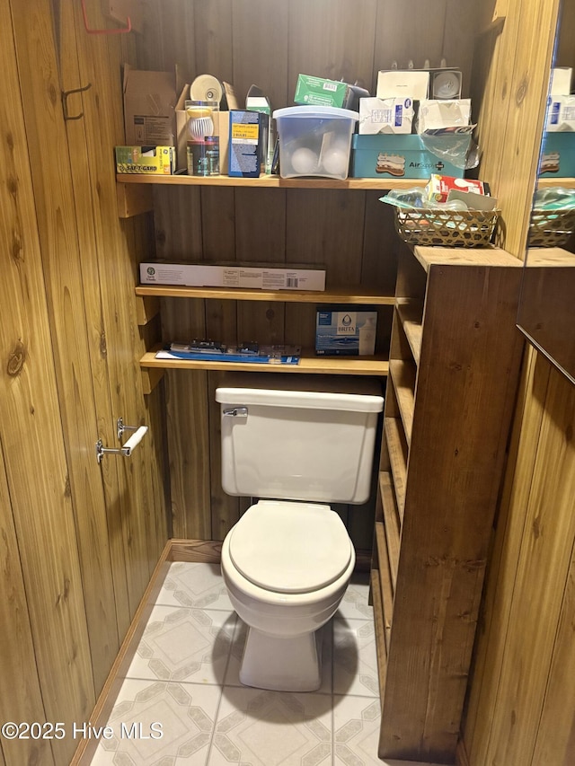 bathroom featuring toilet, wood walls, and tile patterned floors