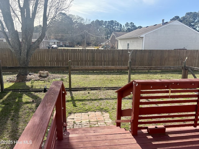 wooden terrace featuring a fenced backyard and a lawn