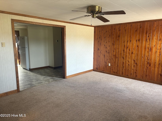 empty room featuring carpet floors, ornamental molding, wood walls, and ceiling fan