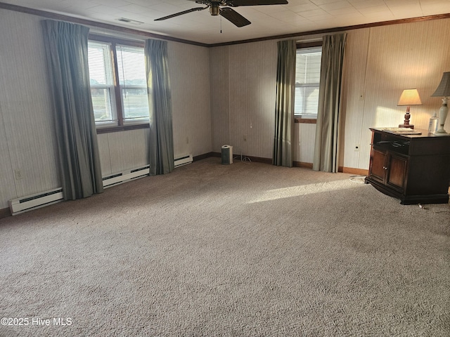 carpeted empty room featuring a baseboard heating unit, ornamental molding, visible vents, and a ceiling fan