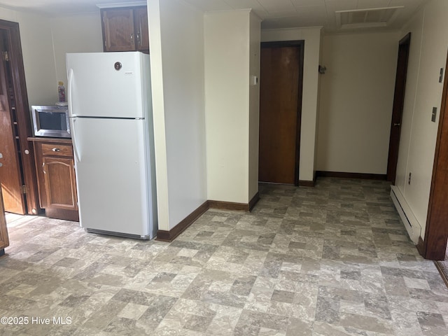 kitchen with a baseboard heating unit, stainless steel microwave, baseboards, freestanding refrigerator, and stone finish floor