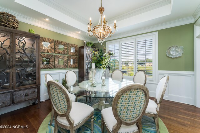 dining room featuring a wainscoted wall, a tray ceiling, wood finished floors, and a chandelier