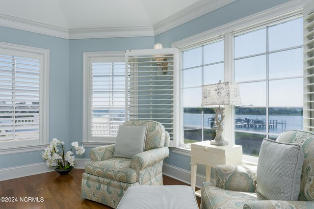 sitting room with a water view, baseboards, ornamental molding, wood finished floors, and vaulted ceiling