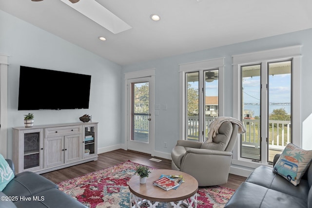 living room featuring recessed lighting, baseboards, vaulted ceiling with skylight, and dark wood-style flooring