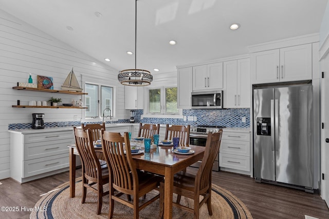 kitchen with dark wood-type flooring, backsplash, stainless steel appliances, light countertops, and vaulted ceiling