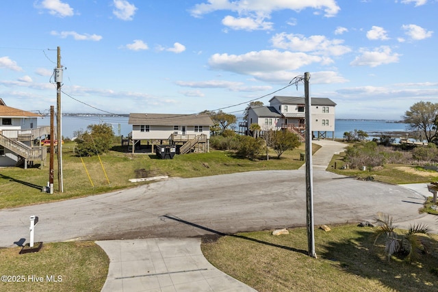 view of road with stairway, a water view, and driveway