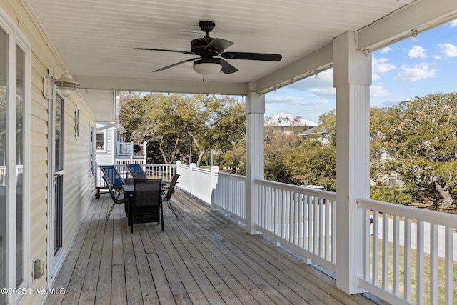 wooden deck with outdoor dining area and a ceiling fan