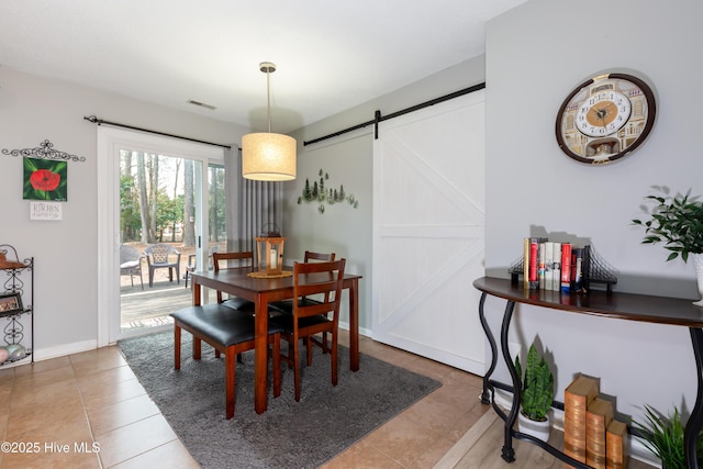 dining space with tile patterned flooring, visible vents, baseboards, and a barn door