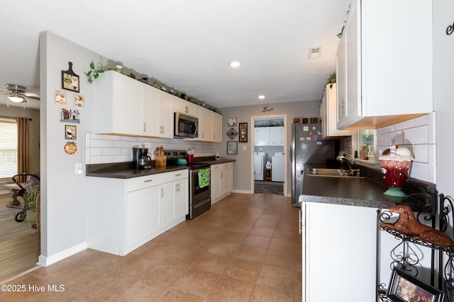 kitchen featuring stainless steel appliances, dark countertops, white cabinetry, and a sink