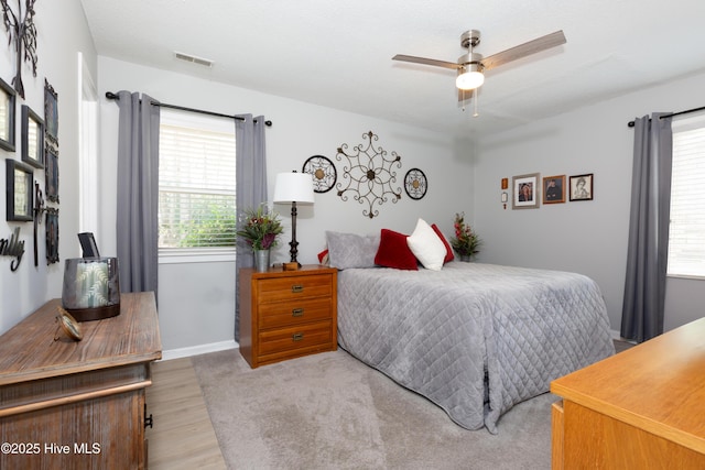 bedroom with baseboards, visible vents, and wood finished floors