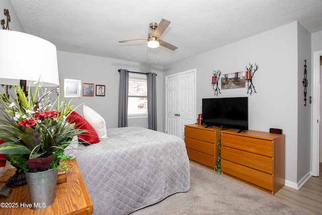 bedroom featuring a textured ceiling, ceiling fan, light wood finished floors, and a closet