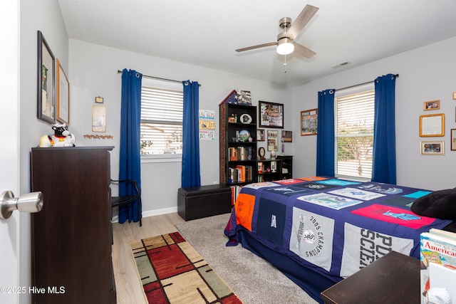 bedroom featuring baseboards, visible vents, ceiling fan, and wood finished floors