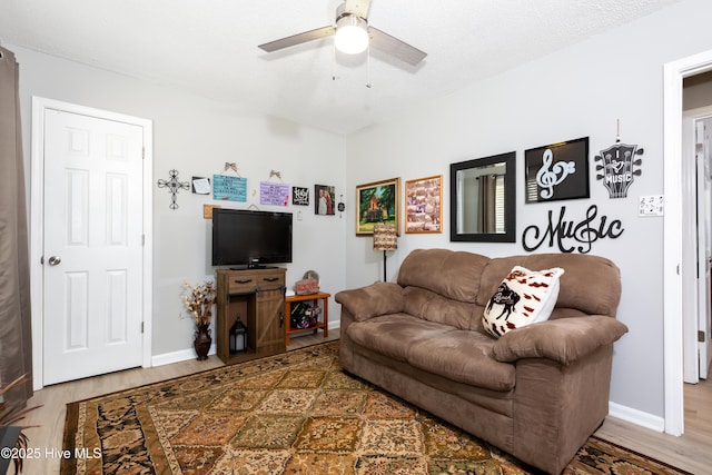 living area featuring ceiling fan, baseboards, and wood finished floors