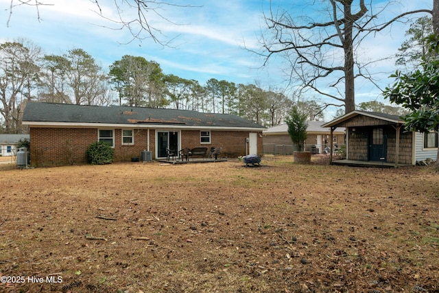 rear view of property with brick siding, fence, and central air condition unit