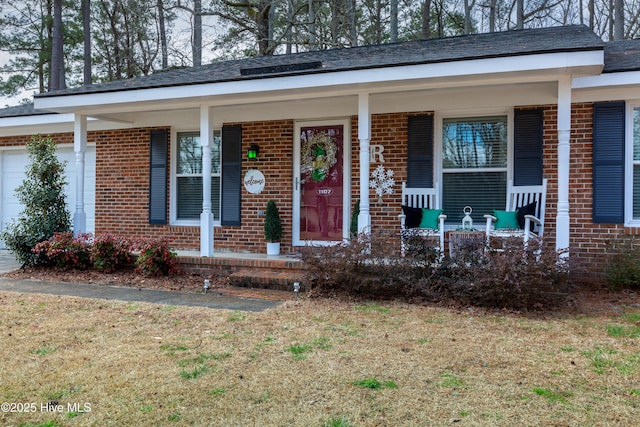 view of front of house with a porch, brick siding, and a garage