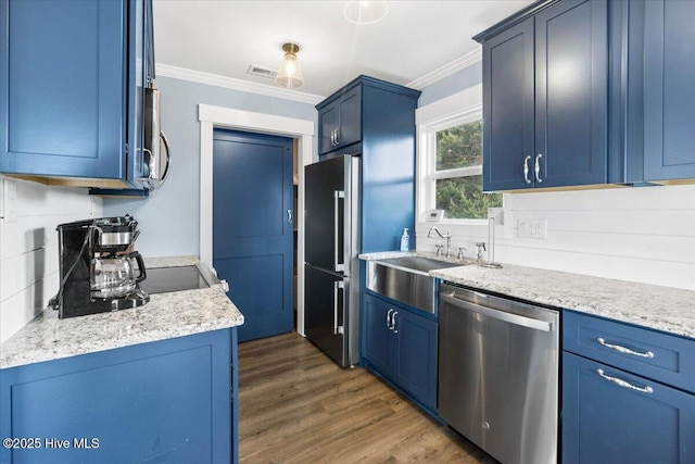 220 W Dolphin Dr, Oak Island, NC 28465 - kitchen with stainless steel appliances, blue cabinets, ornamental molding, a sink, and dark wood-style flooring