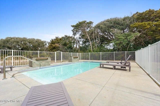 220 W Dolphin Dr, Oak Island, NC 28465 - view of swimming pool featuring a patio, view of wooded area, and fence