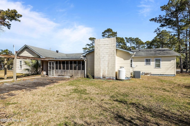 rear view of property featuring a sunroom, a chimney, cooling unit, and a lawn