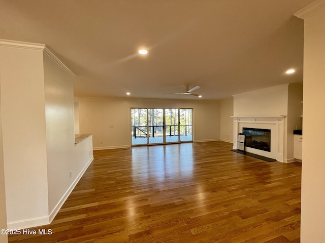 unfurnished living room with recessed lighting, a glass covered fireplace, ceiling fan, wood finished floors, and baseboards