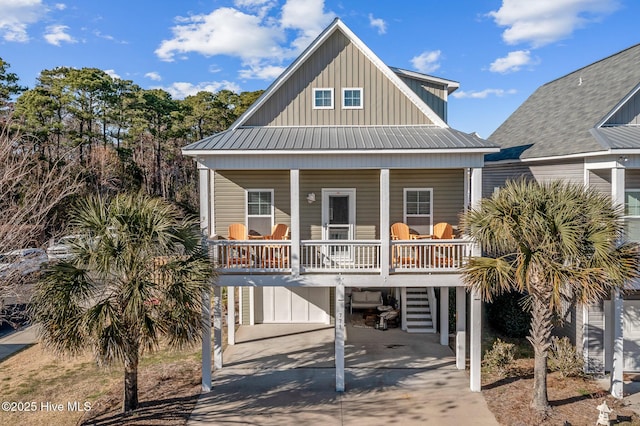 beach home featuring concrete driveway, metal roof, a carport, covered porch, and board and batten siding