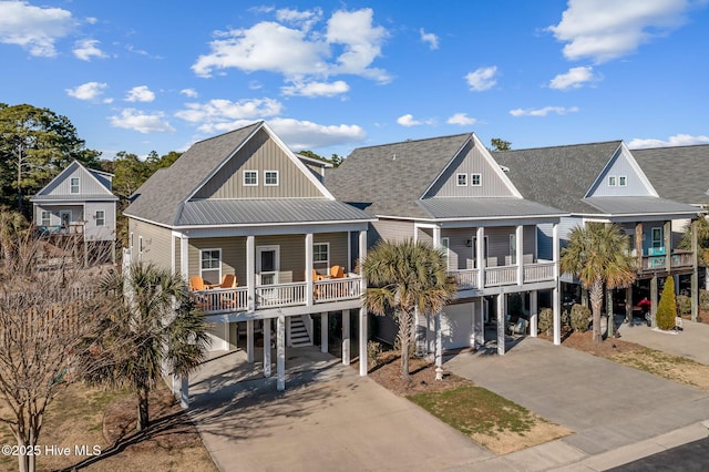 coastal home featuring covered porch, driveway, a carport, and roof with shingles