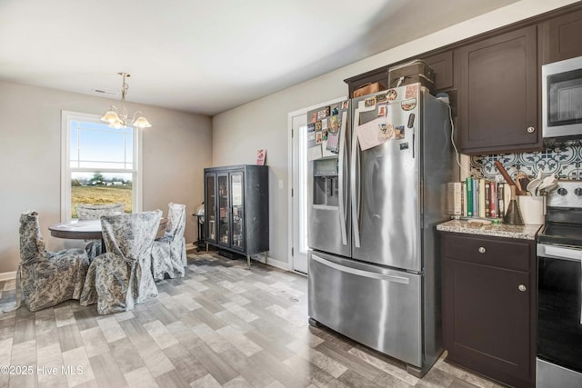 kitchen with dark brown cabinetry, pendant lighting, stainless steel appliances, and an inviting chandelier