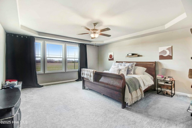 bedroom featuring ceiling fan, baseboards, a raised ceiling, and carpet flooring