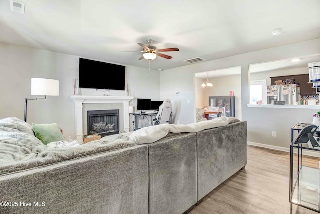 living room featuring light wood-style floors, visible vents, a fireplace, and baseboards