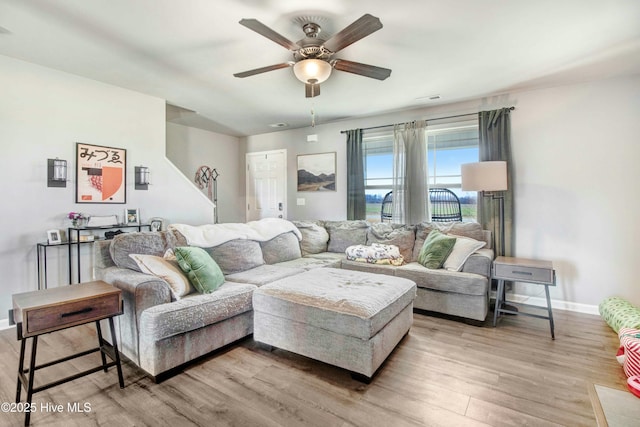 living room featuring ceiling fan, light wood finished floors, visible vents, and baseboards