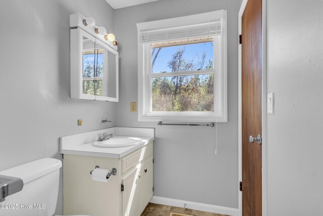 half bath with toilet, vanity, and baseboards