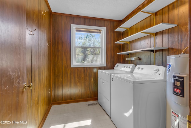 laundry area featuring laundry area, water heater, independent washer and dryer, and wooden walls