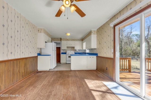 kitchen featuring a wainscoted wall, white appliances, light wood finished floors, and wallpapered walls