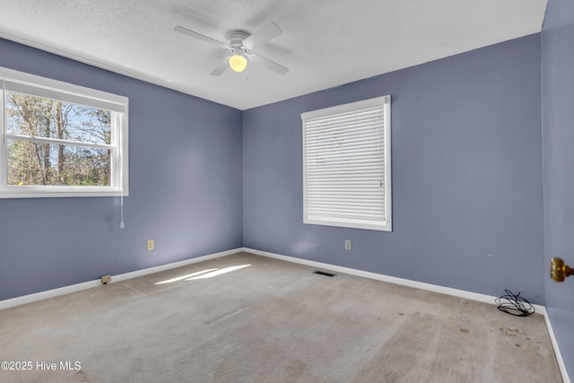 carpeted spare room with visible vents, a textured ceiling, baseboards, and a ceiling fan