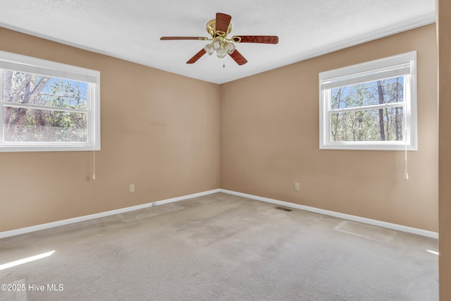 unfurnished room with visible vents, carpet floors, a wealth of natural light, and baseboards